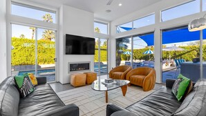 A modern living room with leather sofas, a glass coffee table, a flat-screen TV, and a fireplace. - Modern Desert Oasis – Luxury Retreat (Palm Springs)