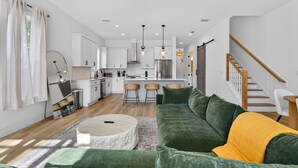 A modern kitchen with white cabinets, a central island, and a dining area with bar stools. - Private Pool! Game Room! 3BR Townhome Nr Downtown (St. Augustine)