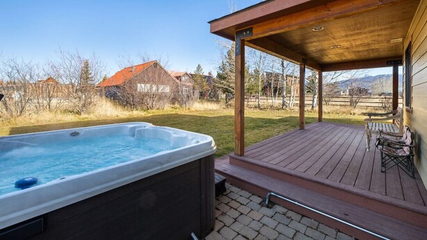 A hot tub on a wooden deck with a covered area and a bench. - Charming Two Story Home with Hot Tub (Driggs)