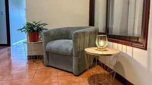 A corner room with a grey sofa, a small round table with a lamp, and a potted plant. - Brumas de Valverde (Monteverde)