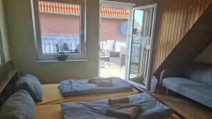 A room with two beds, a sofa, and a sliding glass door leading to an outdoor area. - Hotel Pension Friesenruh (Esens)