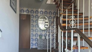 A staircase with white balusters and wooden steps, leading to a landing with a patterned wall and a round mirror. - Hotel Pension Friesenruh (Esens)
