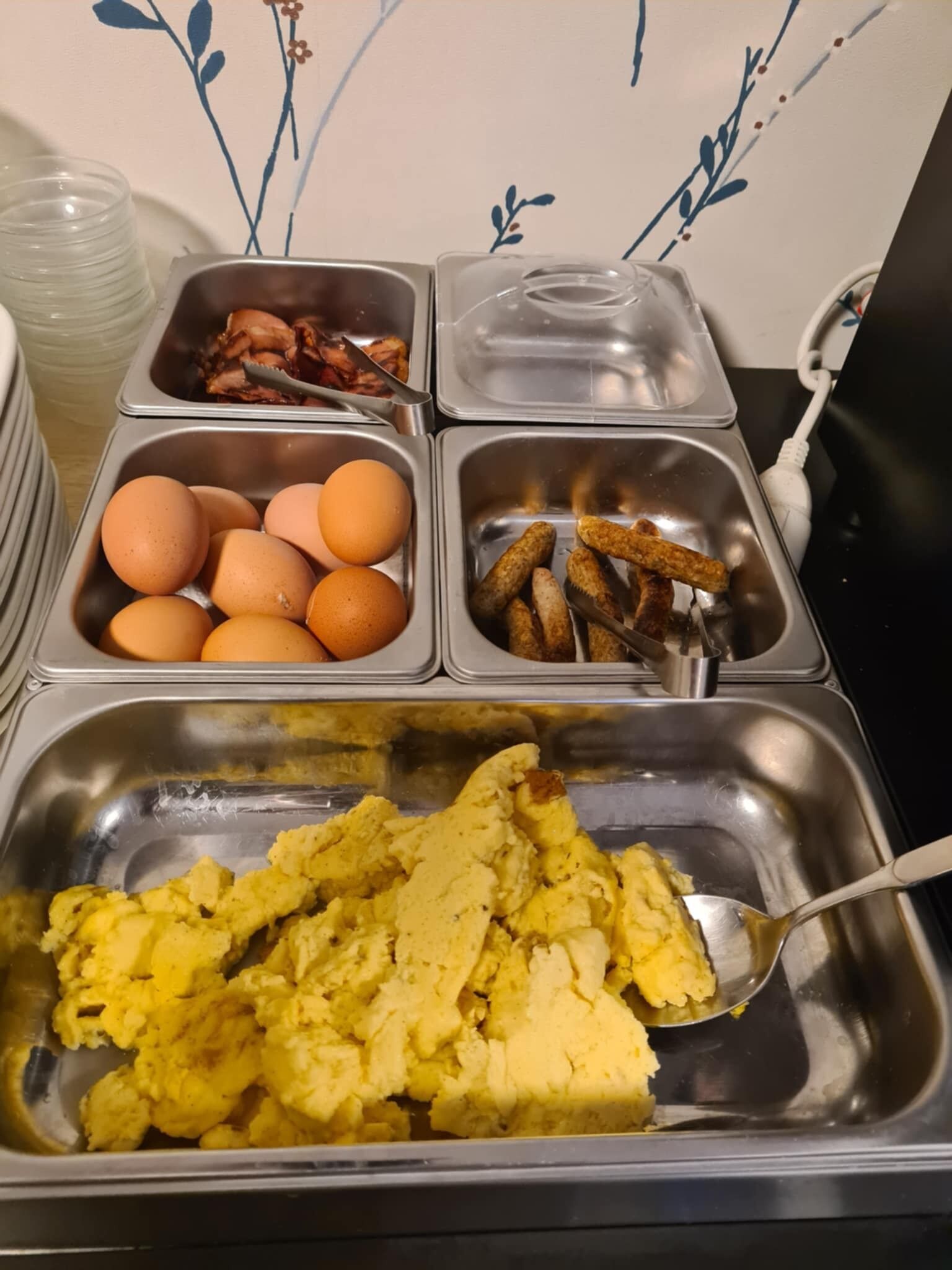 A buffet with scrambled eggs, bacon, sausages, and eggs.