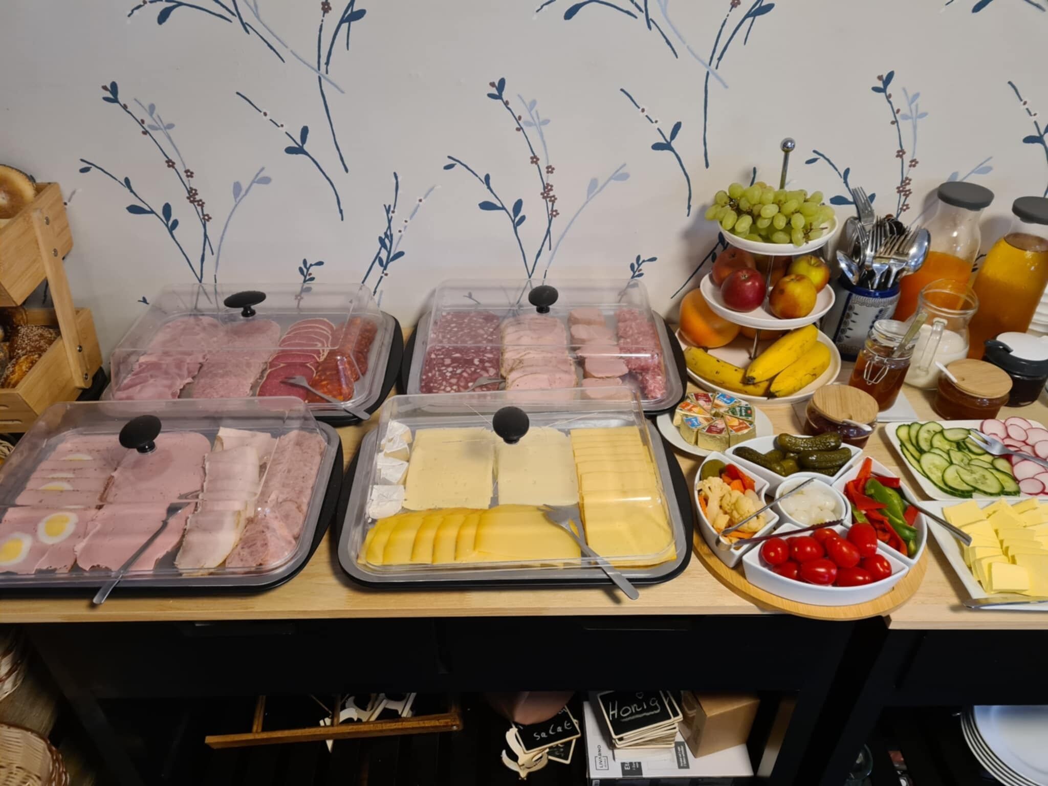 A buffet with various food items including meats, cheeses, fruits, and vegetables.