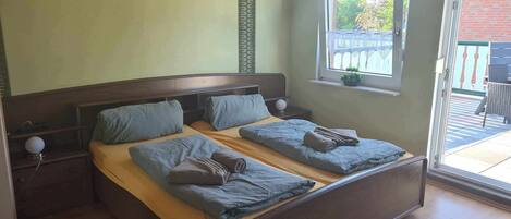 Ein Doppelbett mit Holz-Kopfteil, zwei Nachttische und ein Fenster mit Blick ins Freie.