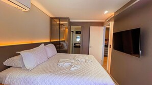 Hotelkamer met een bed, een televisie, een spiegel en een badkamers deur.
