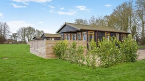 Une cabane en bois avec une cour clôturée, de grandes fenêtres et un toit en pente.