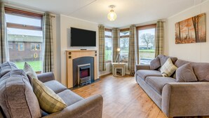 Ein Wohnzimmer mit zwei Sofas, einem Kamin, einem Fernseher und einem Gemälde an der Wand.