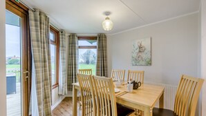 Ein Essbereich mit Holztisch und Stühlen, einem Bild an der Wand und Blick durch das Fenster.