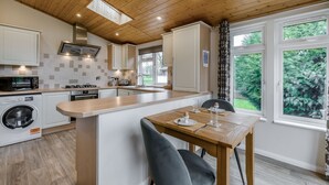 A modern kitchen with wooden ceiling, built-in appliances, and a dining area with a table and chairs. - Field View 1 bed No Pets Walnut (Eye)
