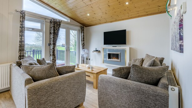 A living room with two sofas, a coffee table, a fireplace, and a TV mounted on the wall. - Field View 1 bed No Pets Walnut (Eye)