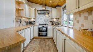 A modern kitchen with white cabinets, a wooden countertop, a built-in oven, and a window with a view of greenery. - Field View 2 bed (S)- Sycamore - sleeps 6 guests  in 2 bedrooms (Eye)