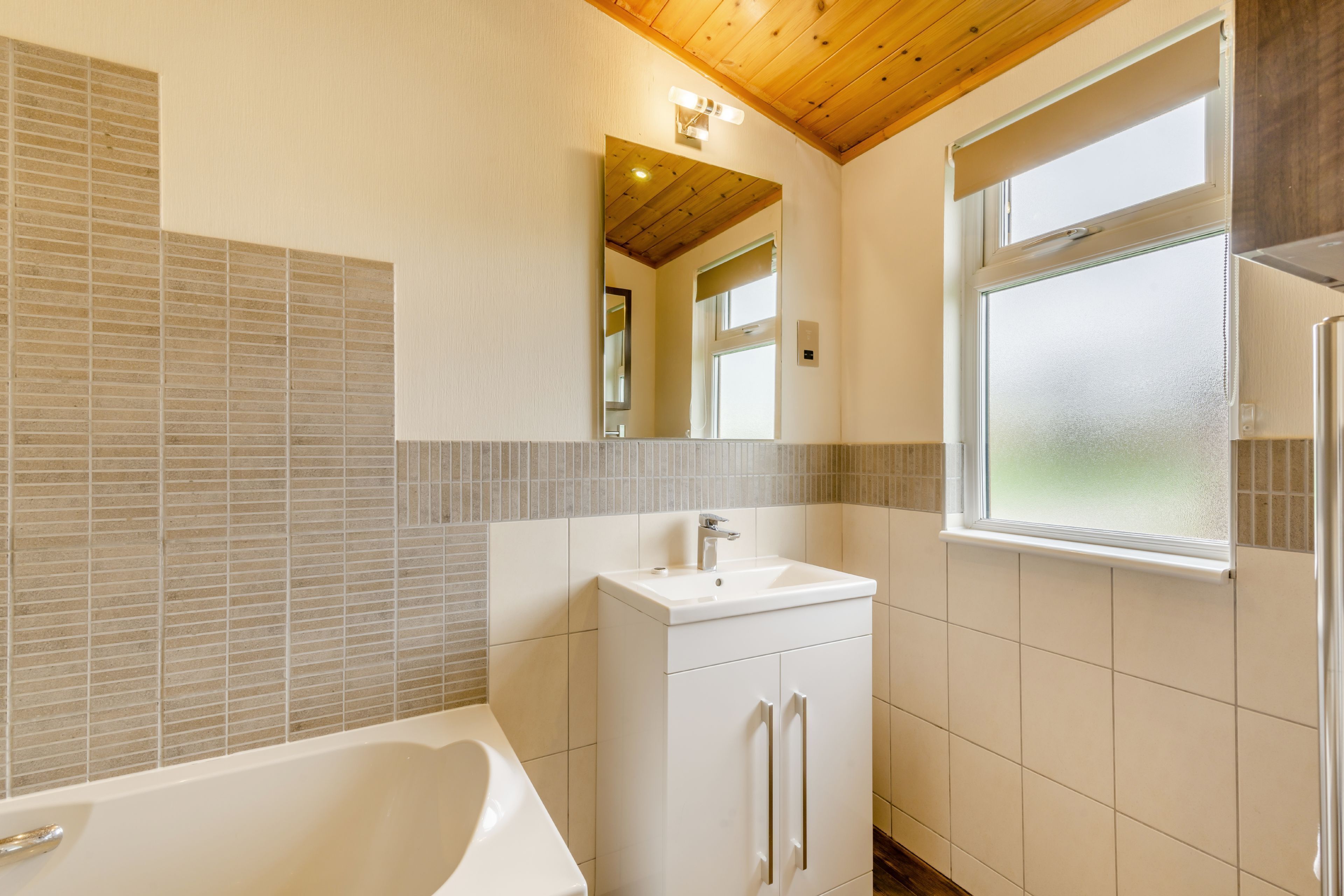 Une salle de bain avec une baignoire, un lavabo, un miroir et une fenêtre.
