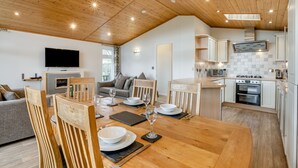 A modern kitchen with wooden cabinets, a built-in oven, and a flat-screen TV. - Field View 2 bed (S)- Spruce - sleeps 6 guests  in 2 bedrooms (Eye)