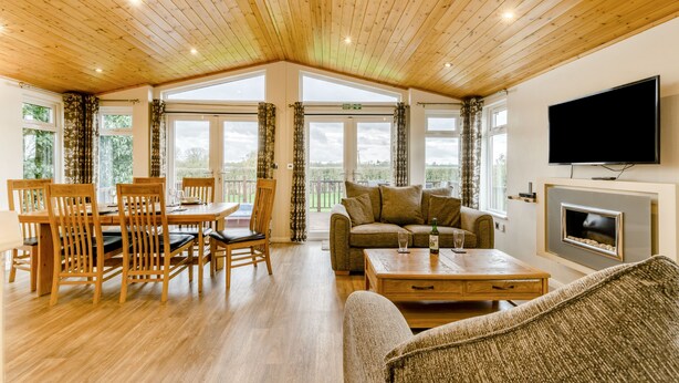 A spacious room with wooden flooring, a dining table with chairs, a sofa, a television, and a fireplace. - Field View 2 bed (S)- Spruce - sleeps 6 guests  in 2 bedrooms (Eye)