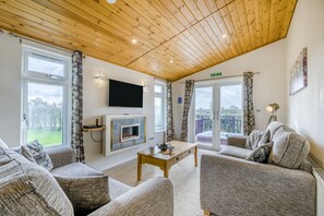 Ein gemütliches Wohnzimmer mit Kamin, Sofas und Fernseher.