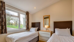 A hotel room with two beds, a dresser, a mirror, and a window with curtains. - Field View 2 bed - Hazel - sleeps 6 guests  in 2 bedrooms (Eye)