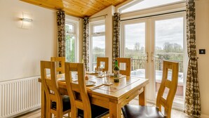 A dining area with a wooden table, chairs, and a bottle of beer. - Field View 2 bed - Hazel - sleeps 6 guests  in 2 bedrooms (Eye)