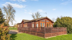A wooden cabin with a fenced yard, large windows, and a clear sky. - Field View 2 bed - Hazel - sleeps 6 guests  in 2 bedrooms (Eye)