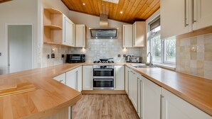 A modern kitchen with wooden countertops, white cabinets, a built-in oven, and a window providing natural light. - Field View 2 bed - Hazel - sleeps 6 guests  in 2 bedrooms (Eye)