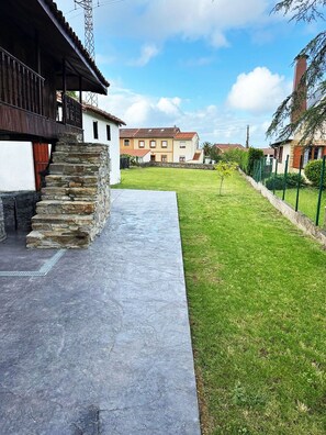 A courtyard with a stone staircase, a paved walkway, and a grassy area.