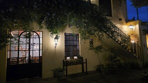 Un bâtiment doté d’une entrée fermée par un portail, d’un escalier et de plantes en pot.