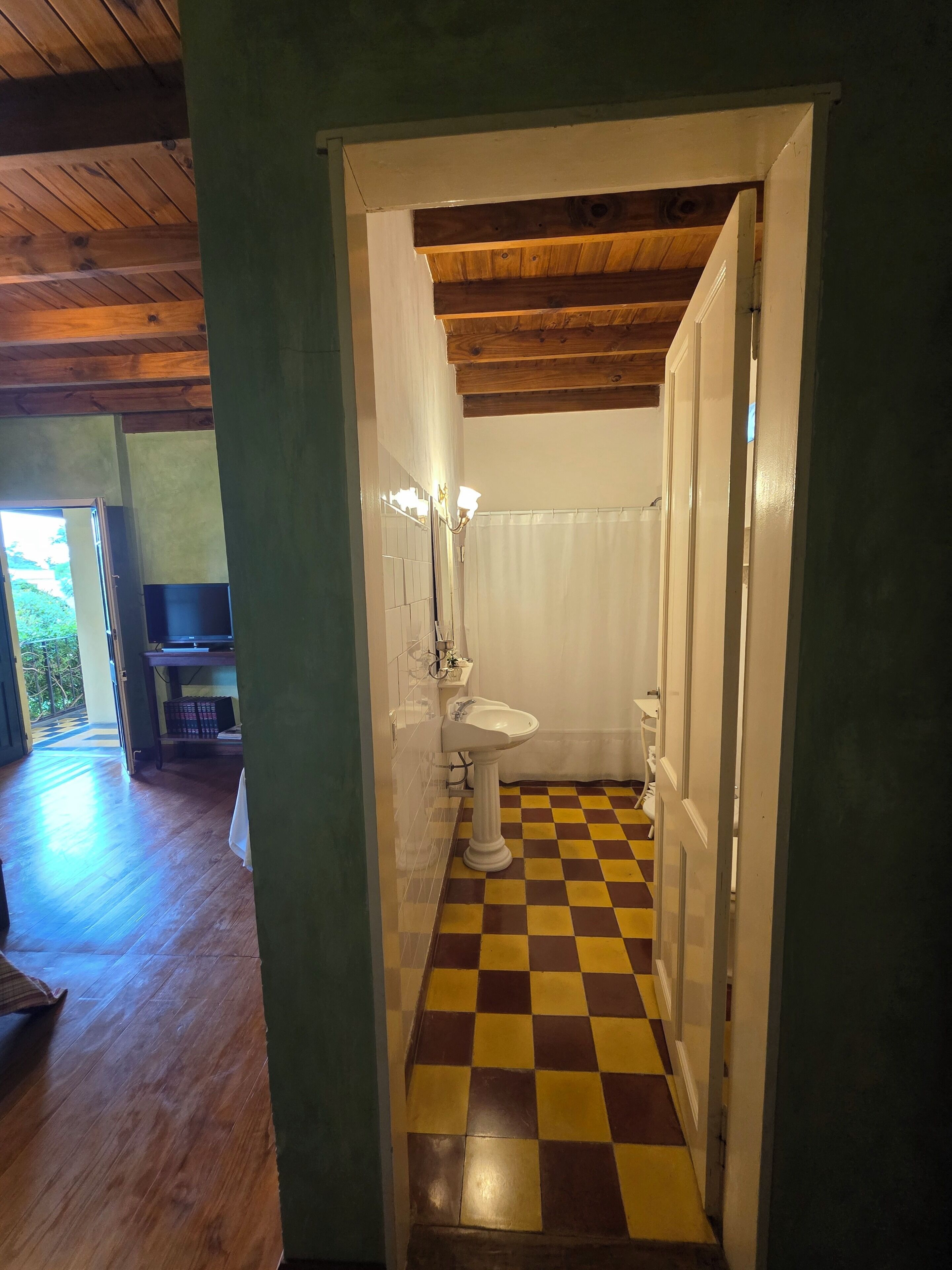 Une salle de bain avec un carrelage à motifs, un lavabo sur pied et un rideau de douche.