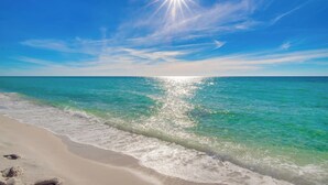 A beach with clear turquoise water, white sand, and a bright sun in the sky. - Newly Renovated 4th-Floor Gulf Front Condo – A Luxurious Coastal Retreat! Sleeps 10 (Navarre)