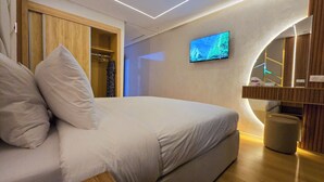 A modern bedroom with a bed, a television mounted on the wall, and a wooden wardrobe. - Luxury Living - Near to football stadium (Tangier)