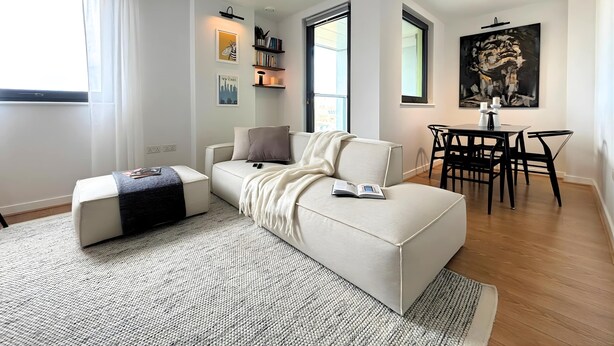 A modern living room with a sofa, a coffee table, a dining area with a table and chairs, and a large abstract painting on the wall. - The Designer Skyline (Greater London)