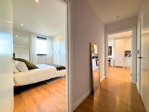 Une chambre moderne avec un lit, un grand miroir et une vue sur la cuisine.
