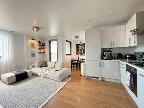 A modern apartment with a living room, dining area, and kitchen. - The Designer Skyline (Greater London)