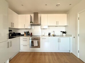 Une cuisine moderne avec des meubles blancs, une cuisinière en acier inoxydable et un four.