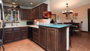 A kitchen with wooden cabinets, a microwave, and a large island with a blue countertop. - Pool Days, Play Days, Paws Welcome (Cottonwood)