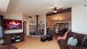 A living room with a fireplace, leather sofas, a TV, and a dining area. - Pool Days, Play Days, Paws Welcome (Cottonwood)