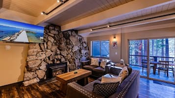 A cozy living room with a stone wall, a fireplace, a wooden coffee table, and a sofa with cushions.