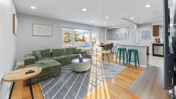 A modern living room with a green sectional sofa, a round coffee table, and a dining area with stools.