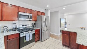 A modern kitchen with stainless steel appliances, wooden cabinets, and a granite countertop.