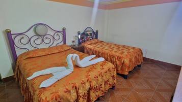 Habitación con dos camas, cada una con colcha estampada y toalla blanca con forma de cisne.