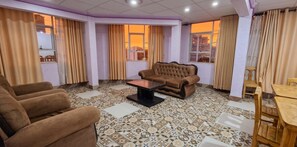 A living room with a brown sofa, a wooden coffee table, and a patterned floor. - Hotel Puesta de Sol (Uyuni)