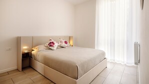 Une chambre moderne avec un grand lit, des lampes de chevet et une fenêtre ornée de rideaux légers.