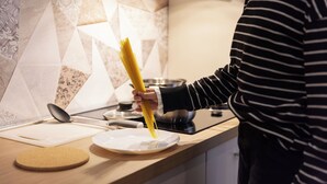 Un comptoir de cuisine avec une assiette, un dessous de verre en liège et une personne tenant une assiette de spaghettis.