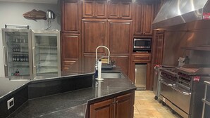 Eine Küche mit Holzausstattung, einem Edelstahlkühlschrank, einer Spüle und einem eingebauten Backofen.