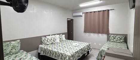 A hotel room with two beds, a ceiling fan, an air conditioning unit, and a television.