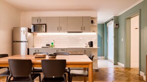 A modern kitchen with a wooden dining table, black chairs, a refrigerator, a microwave, and a coffee maker. - Luxury 1BR Loft in Bellavista | Near Metro Fits 5 (Providencia)
