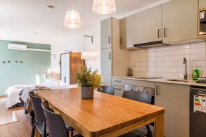 A modern kitchen with a wooden dining table, black chairs, and pendant lighting. - Cozy Studio Bellavista Dining & Hospital Access (Providencia)