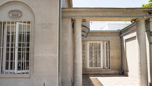 A building entrance with a stone facade, columns, and barred windows. - Cozy Studio Bellavista Dining & Hospital Access (Providencia)