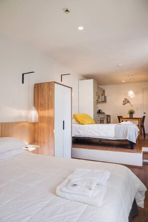Ein Hotelzimmer mit zwei Betten, einem Holzschrank, einem Schreibtisch mit Stuhl sowie einer Pendelleuchte.