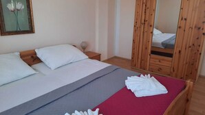 Ein Hotelzimmer mit einem Bett, einem Holzschrank, einem Nachttisch und einem gerahmten Bild an der Wand.
