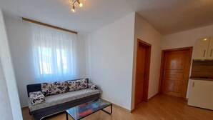 Ein Wohnzimmer mit einer Couch, einem Couchtisch und einer Küchenzeile mit Schränken.